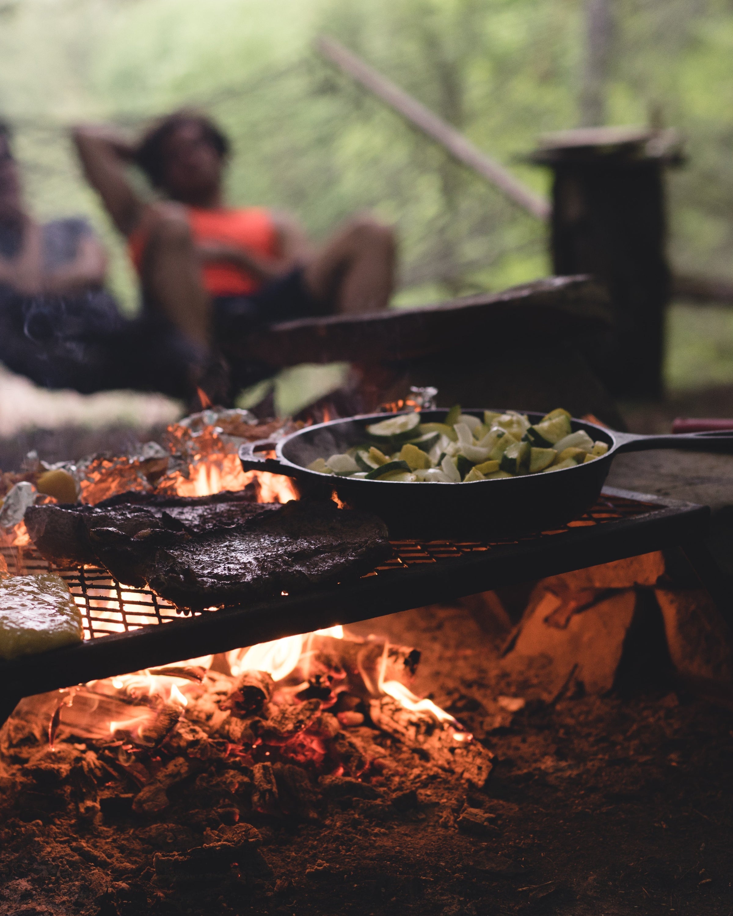 Gift for your husband, cooking over a fire outdoors, meat on the grill and a pan on the embers